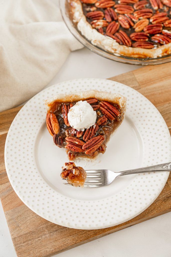 fork taking a slice out of vegan pecan pie without corn syrup on a brown cutting board