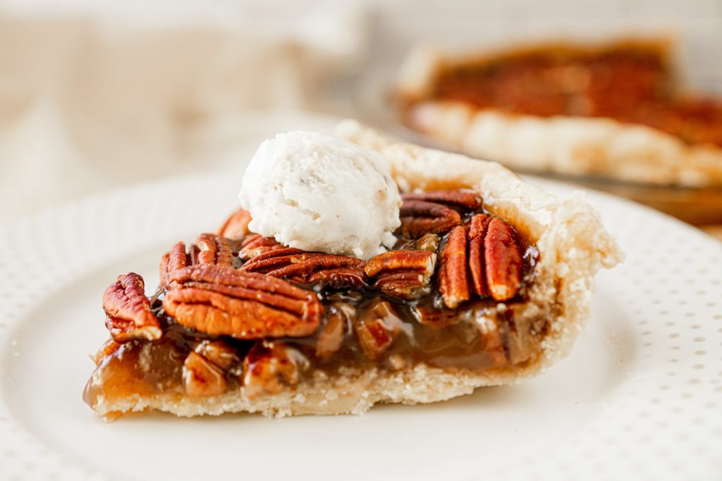 vegan pecan pie without corn syrup  slice on a white plate with ice cream 