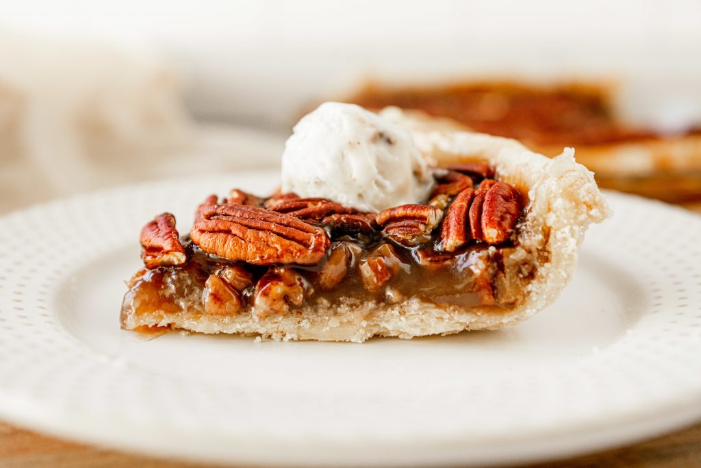 side of the pecan pie that is vegan with ice cream on top of a white plate