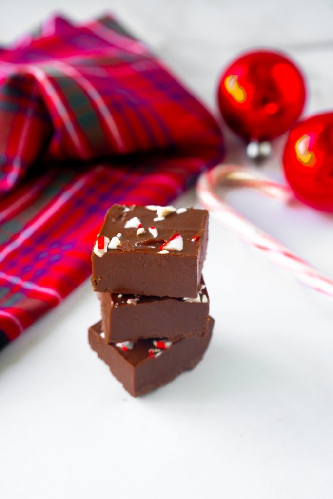 stacked peppermint fudge on a counter with christmas decor