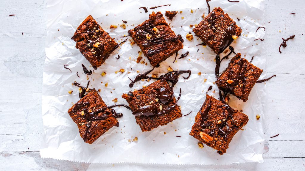 six dairy free pumpkin brownies on parchment paper and drizzled with dark chocolate sauce