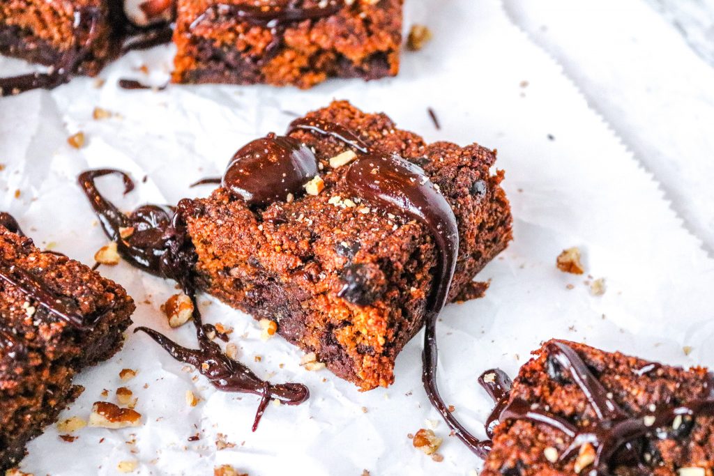 chocolate oozing down the side of a vegan pumpkin brownie on top of white parchment paper