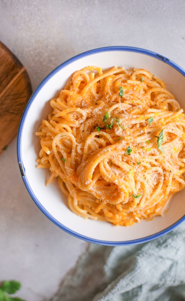 side of a bowl of pumpkin pasta  with fresh herbs 