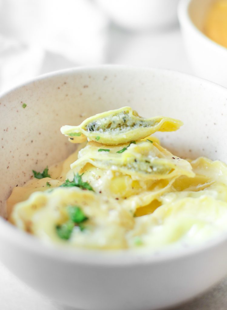 vegan ravioli filling visible as a piece is cut in a bowl