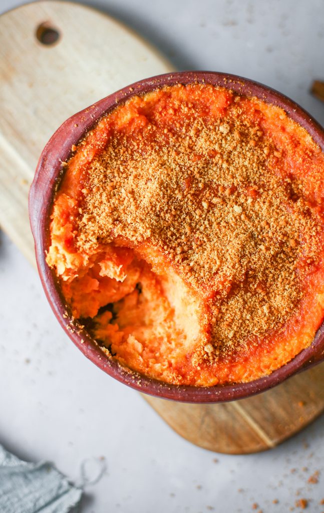 vegan sweet potato casserole with spoon taking a piece out on white counter 