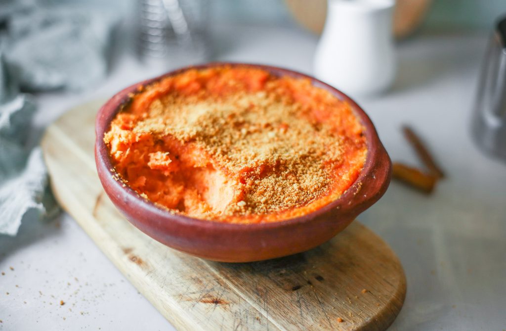 dairy free sweet potato casserole with brown sugar topping sitting on a bread board with blue towel on counter