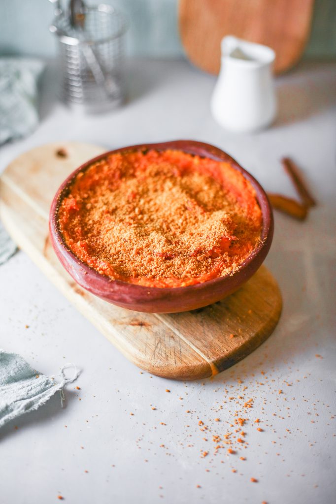 side of healthy sweet potato casserole on cutting board with sticks of cinnamon in the background