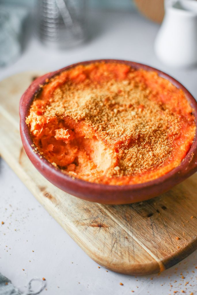 side of gluten free sweet potato casserole in a red bowl on a brown counter