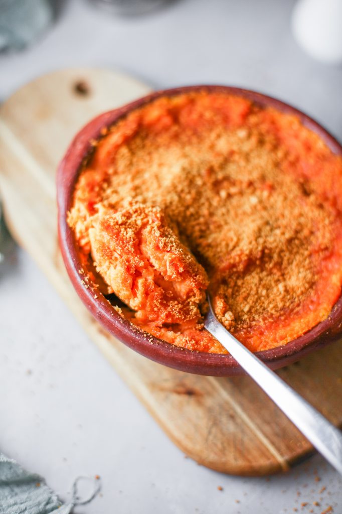 spoon scooping out non dairy sweet potatoes from dish on a brown bread board