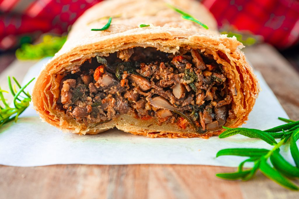 close up on the flaky puff pastry and filling on vegan wellington with mushrooms and rosemary