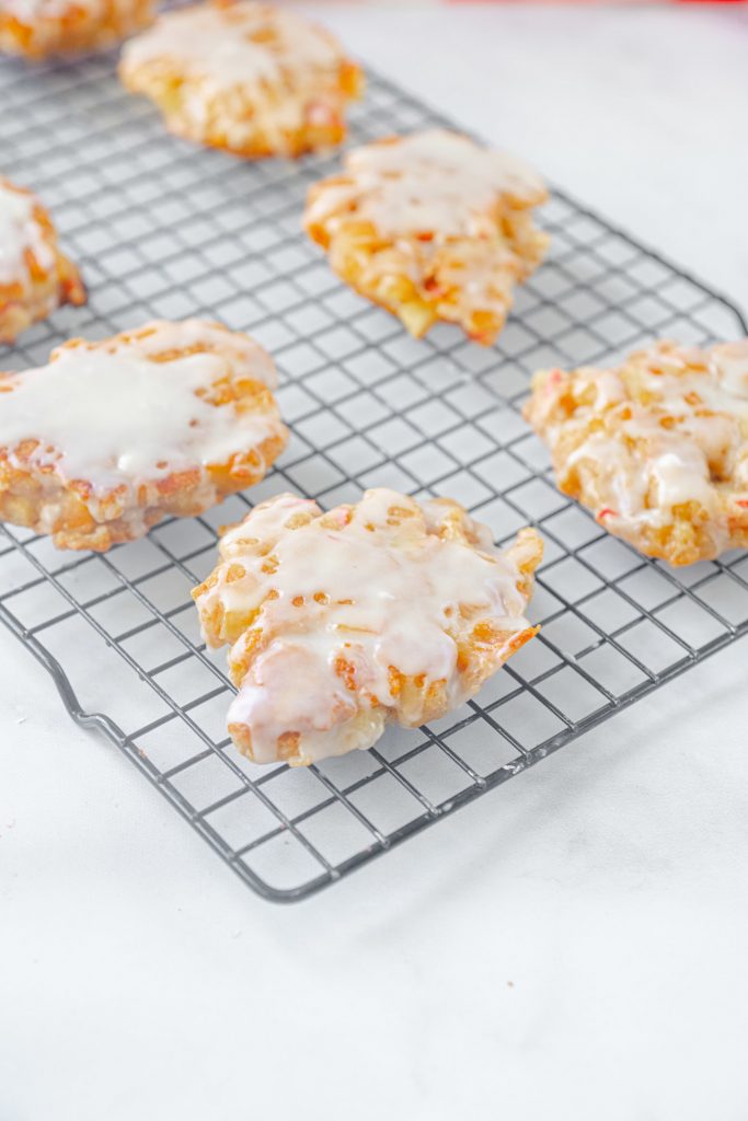 healthy vegan apple fritters with white glaze cooling on cooling rack