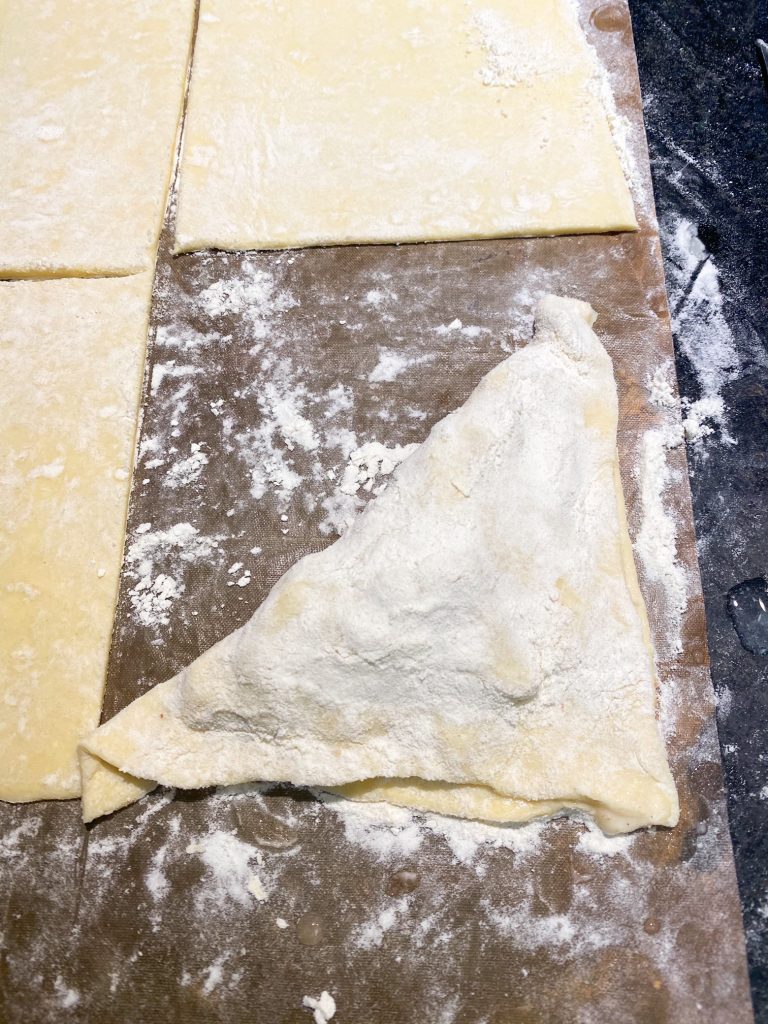 puff pastry dusted with flour being folded over on parchment paper