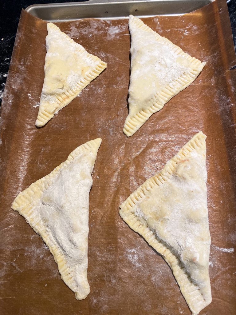 four vegan turnovers on parchment paper before baking