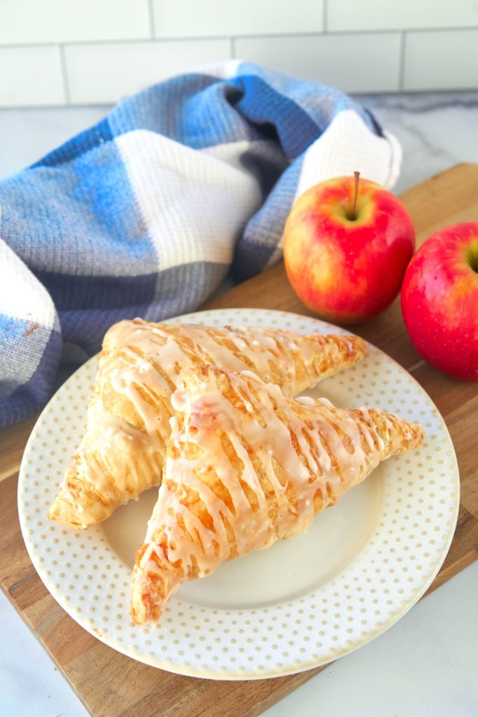 two vegan turnovers on a white plate which is sitting on a brown cutting board