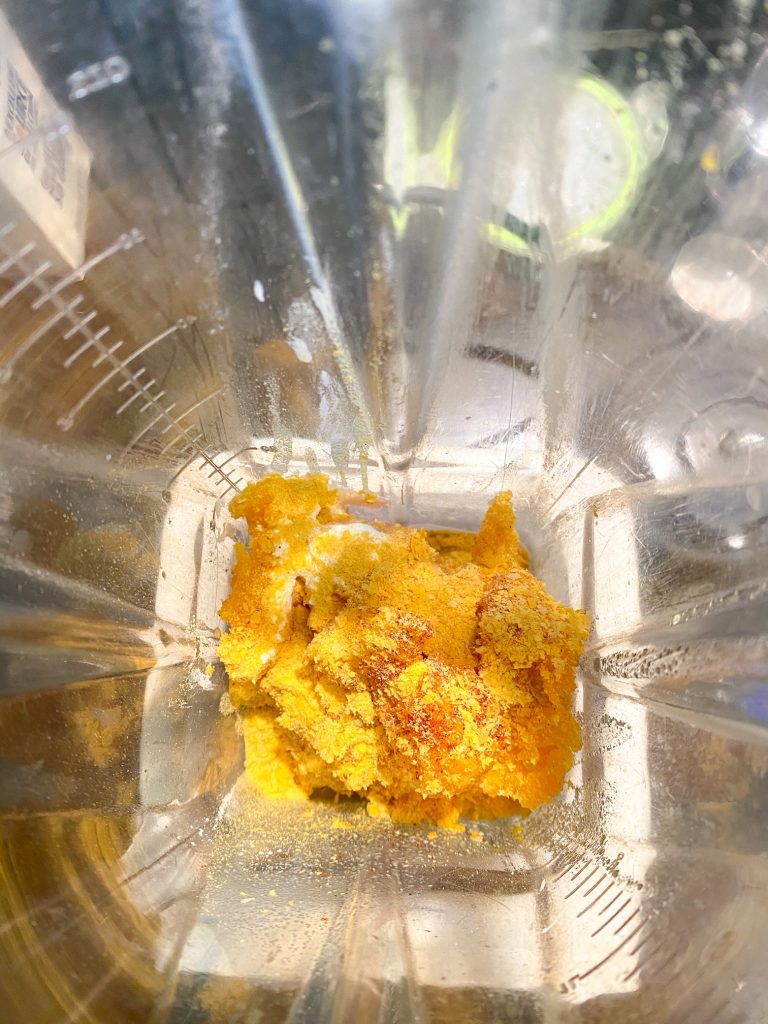 inside of a blender with butternut sqush and nutritional yeast in it