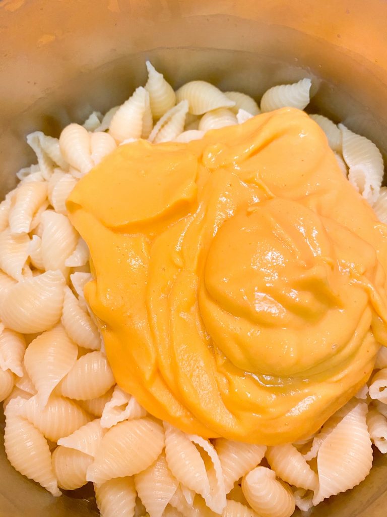 vegan butternut squash cheese sauce going over white pasta in a pot