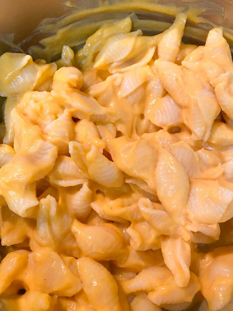 yellow pasta being stirred with vegan butternut squash cheese sauce in a pot