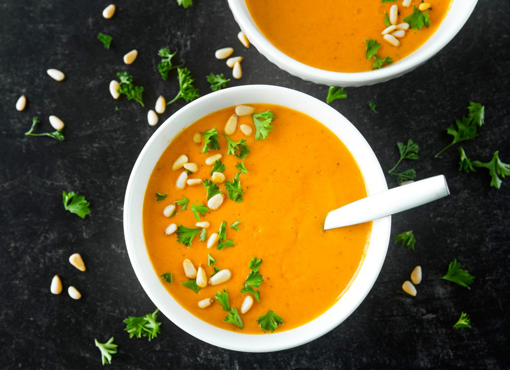 Straight down photo of two bowls of vegan carrot soup on black background