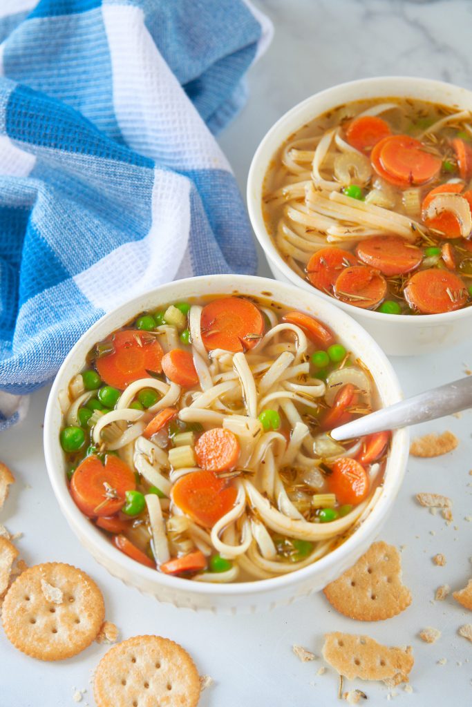 two bowls of vegan chicken noodle soup with crackers