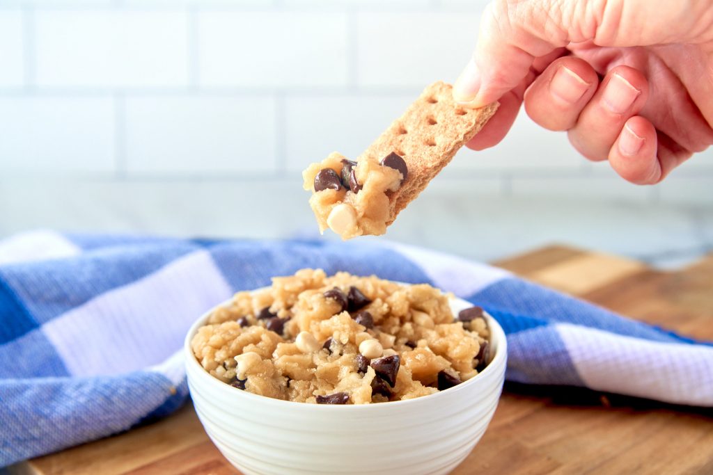 hand scooping up edible vegan cookie dough with a graham cracker