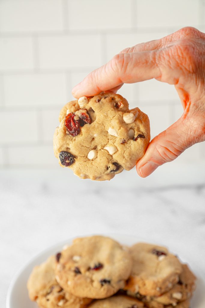 hand holding vegan white chocolate cranberry cookie