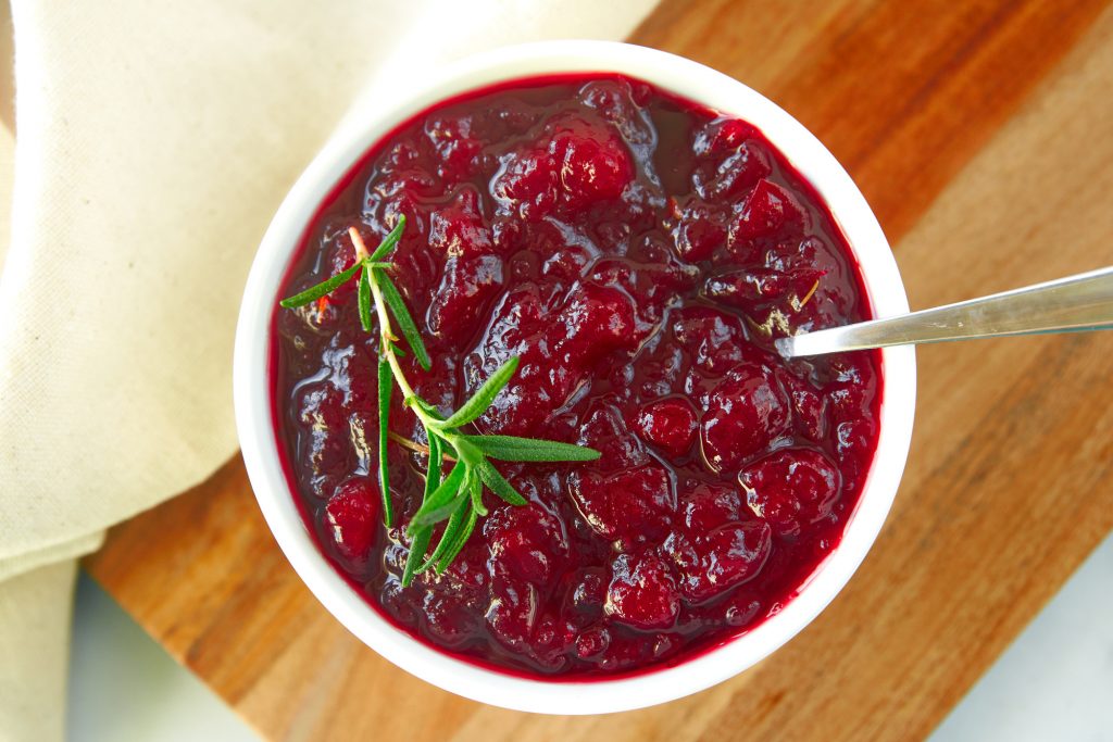 above photo of healthy cranberry sauce with no sugar or dairy with spoon and rosemary on it