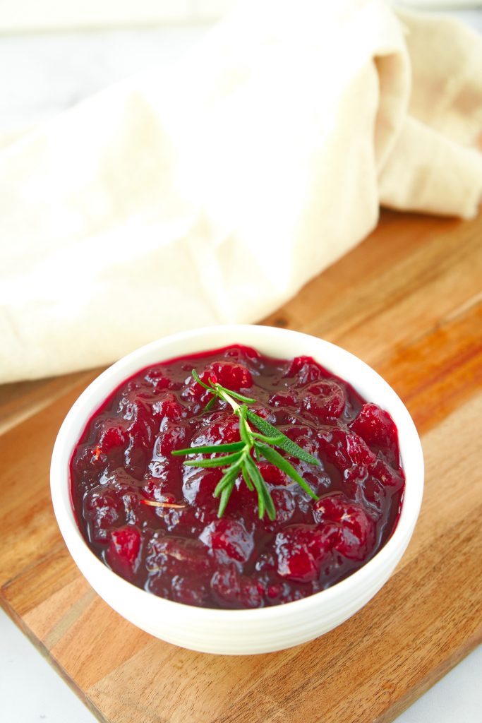 further away photo of homemade vegan cranberry sauce on a bread board with white towel