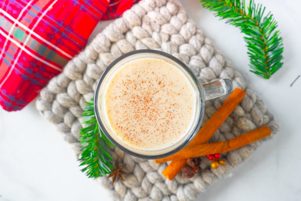 above view of white color dairy free eggnog from above on trivet with brown cinnamon sticks 