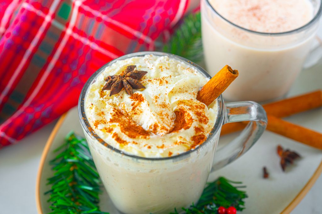 Photo of vegan eggnog with a cinnamon stick garnish. 