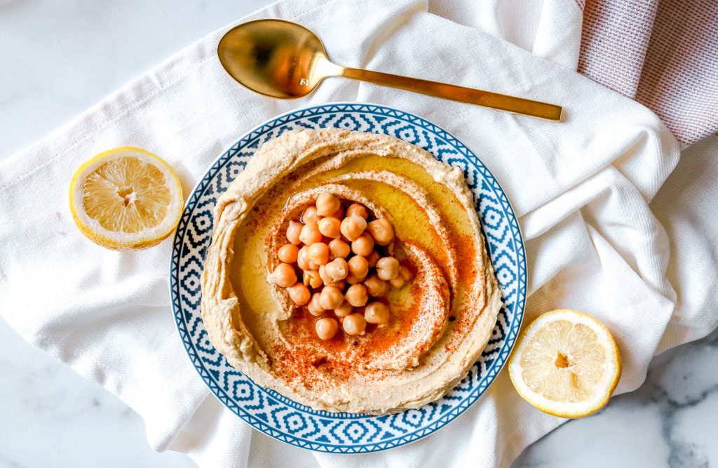 recipe for vegan hummus on plate with lemons and spoon