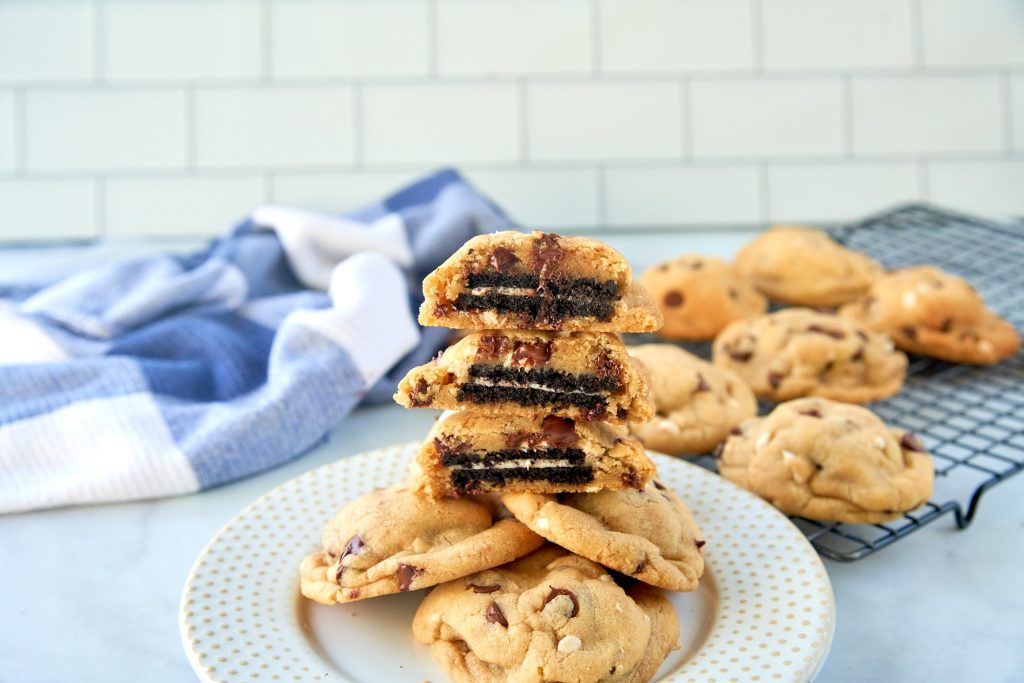 vegan oreo stuffed cookies stacked on plate and cut in half