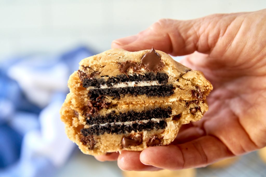 hand holding vegan oreo stuffed cookies cut in half so you can see the insides