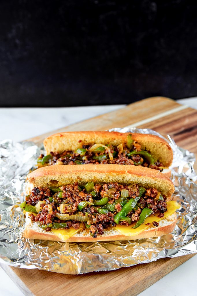 two vegan philly cheesesteak sandwiches on tin foil