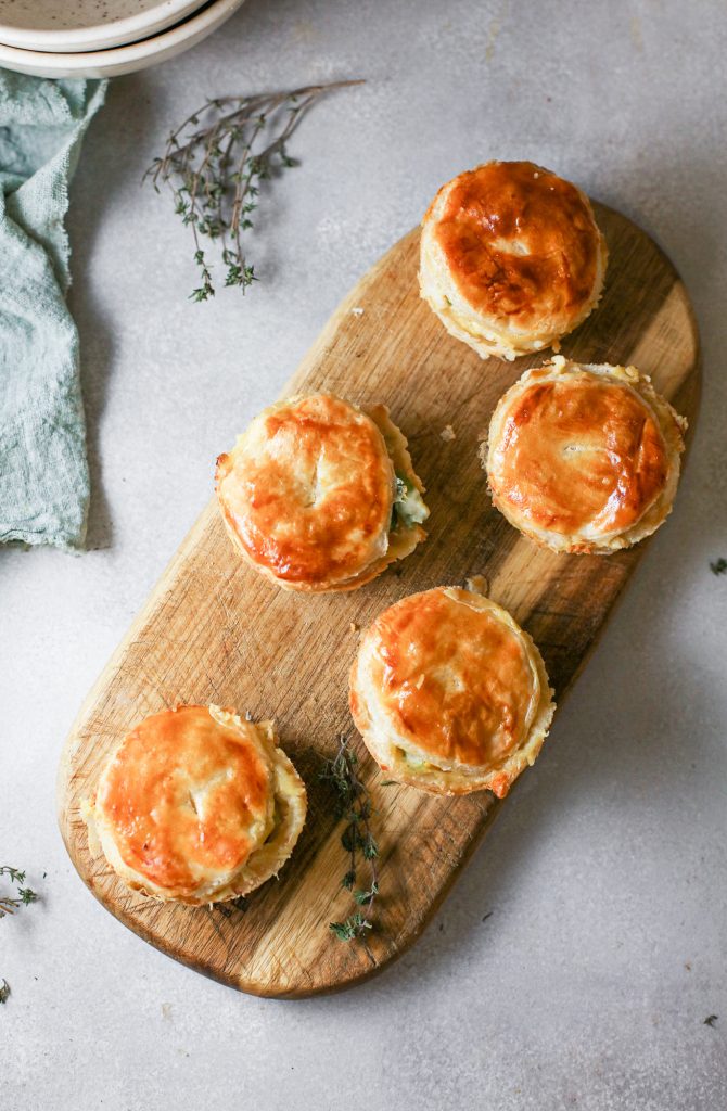 Flatlay of lots of little vegan pot pies lined up on a wooden serving dish