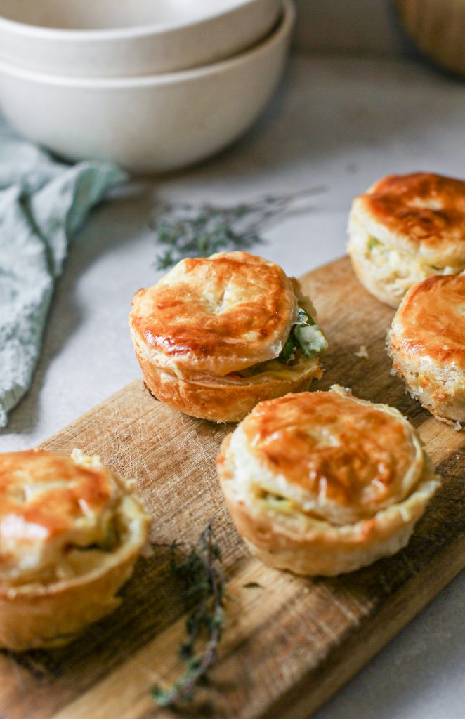 Row of mini pot pies on wooden serving tray. 