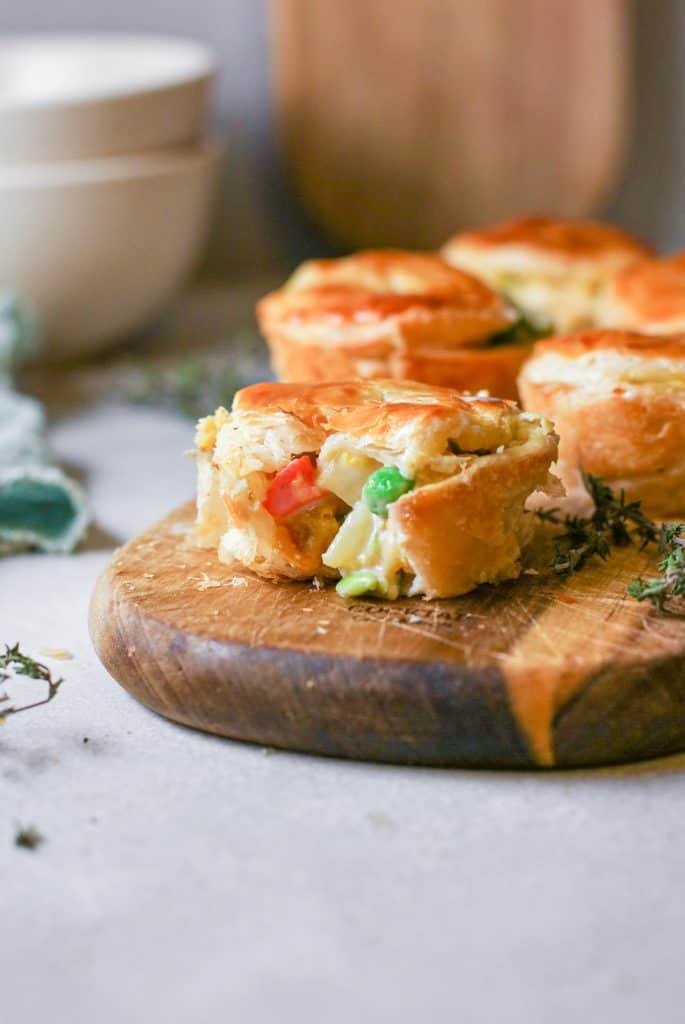 Close up of the inside of one mini pot pie with more in the background on a wooden serving tray.