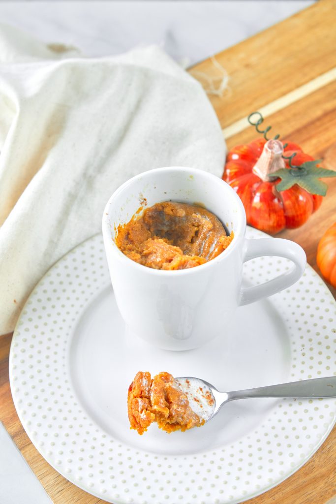 spoon with a scoop of pumpkin mug cake on it on a plate