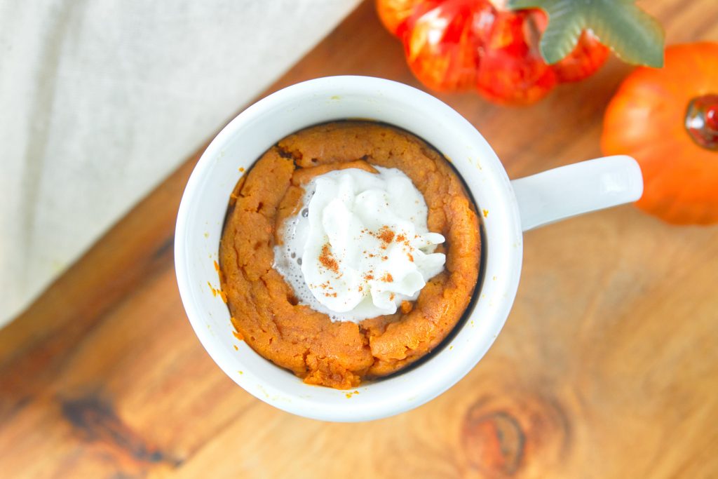 vegan pumpkin mug cake with whipped cream on counter