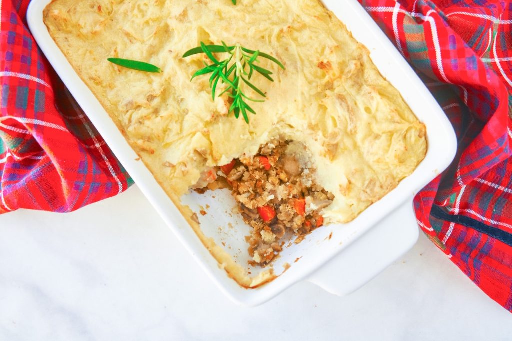 Flatlay of vegan shepherd's pie with lentils in casserole dish with a red hand towel.