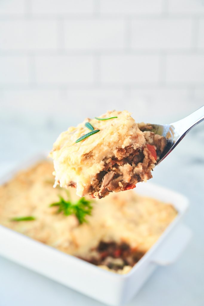 A close up of a bite of vegan cottage pie with lentils on a spoon.