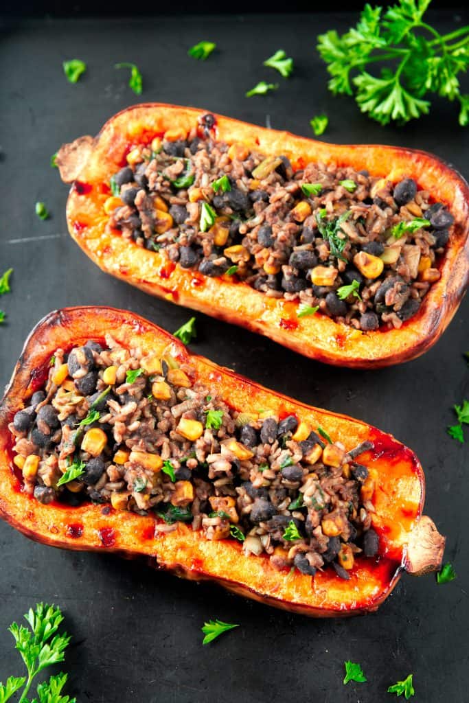 vegan stuffed butternut squash with parsley on a black cooking sheet