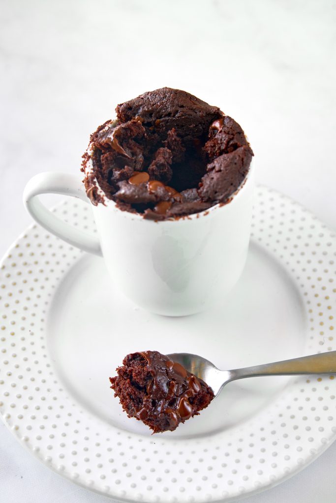 spoon with a scoop of vegan chocolate mug cake on a white plate
