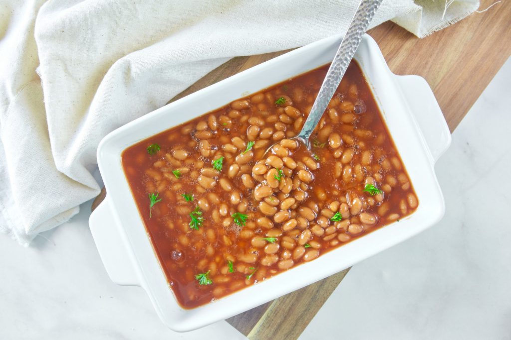 photo of vegan baked beans in a baking dish with a spoon