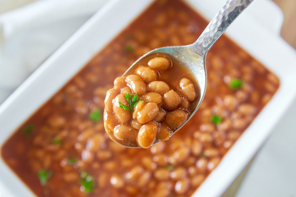 close up of homemade vegan baked beans on a serving spoon