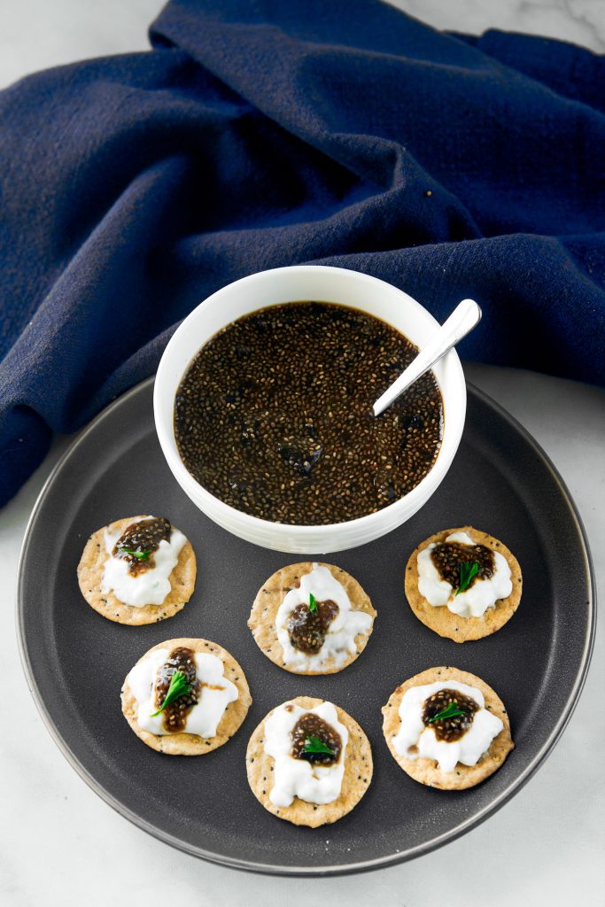 vegan caviar in a bowl with crackers all around it