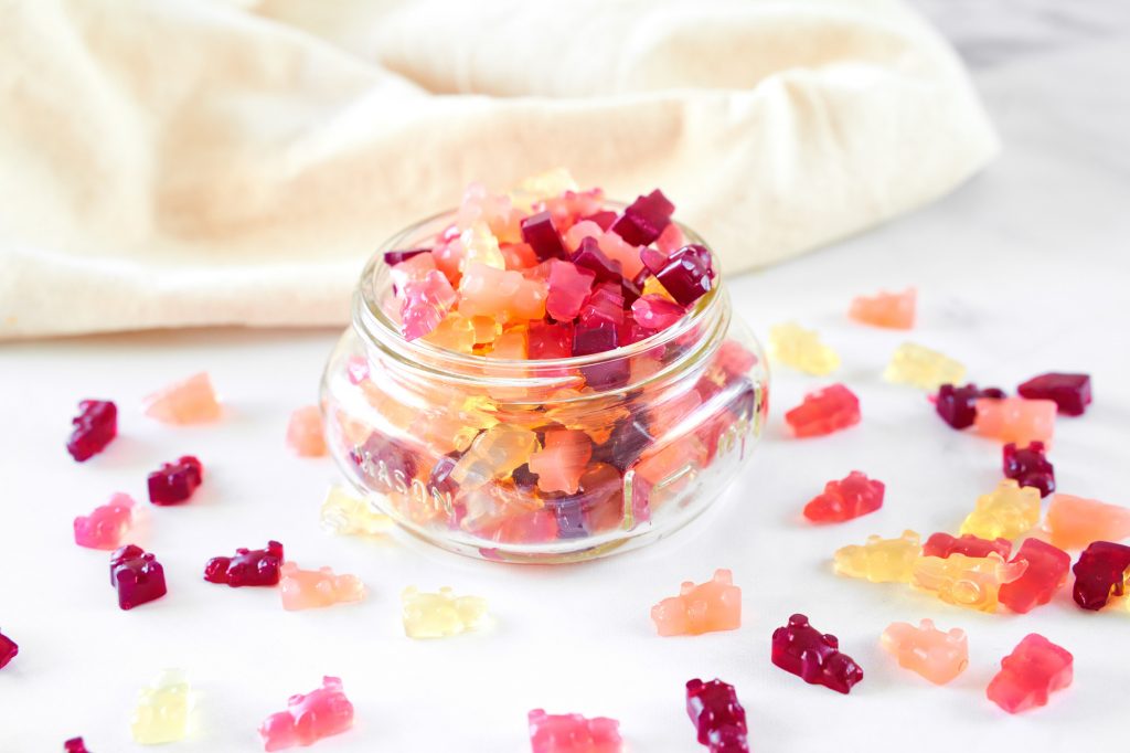 vegan gummy bears in a container spilling over the side and onto the counter