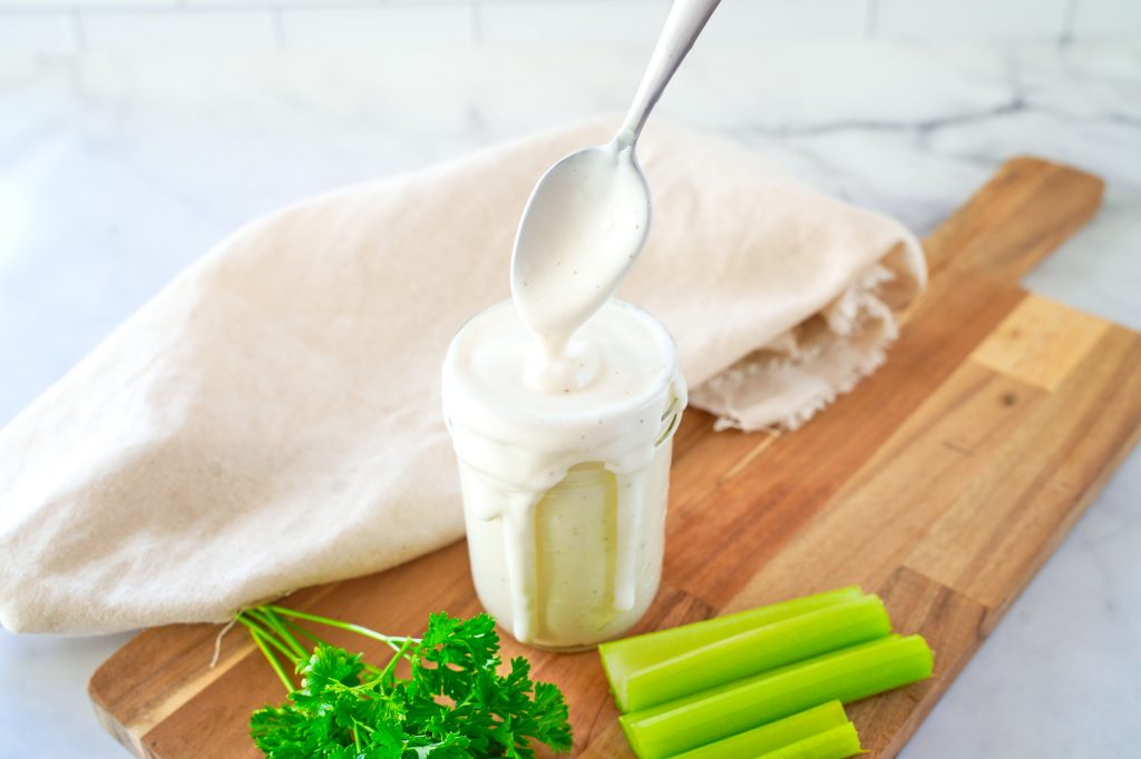 spoon scooping up vegan ranch dressing out of a mason jar