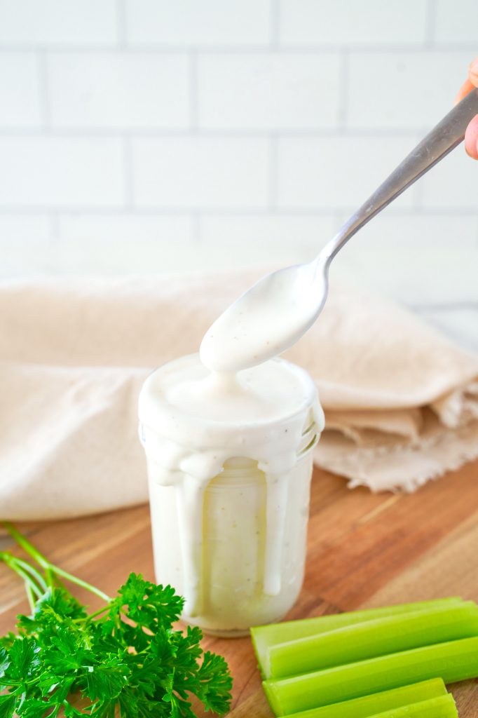 spoon scooping up vegan ranch dressing out of a container