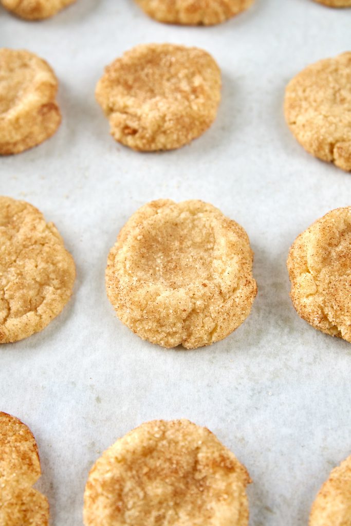 lots of vegan snickerdoodles cooling on parchment paper