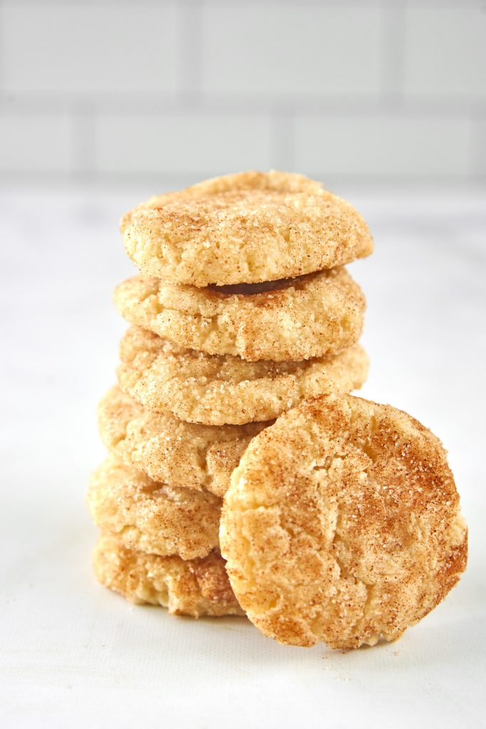 vegan snickerdoodles stacked on a counter with a white background